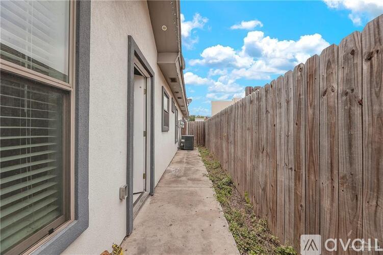 A wooden fence runs along the side of a building with a concrete walkway.