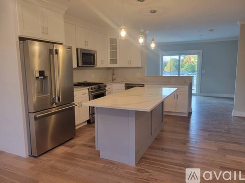 A kitchen with a stainless steel refrigerator and a white island.