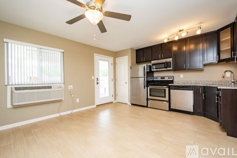 A kitchen with a fan and wooden floors.