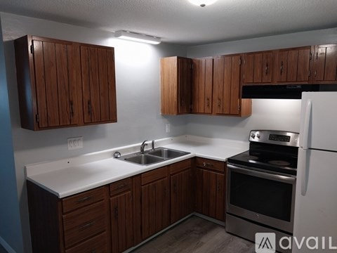 A kitchen with wooden cabinets and a stainless steel refrigerator.
