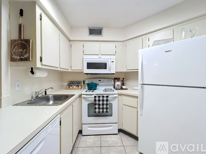 A white refrigerator is in the kitchen with a white oven and microwave.