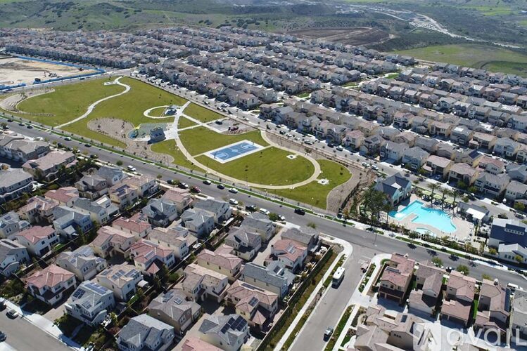 A bird's eye view of a residential area with houses, roads, and a swimming pool.