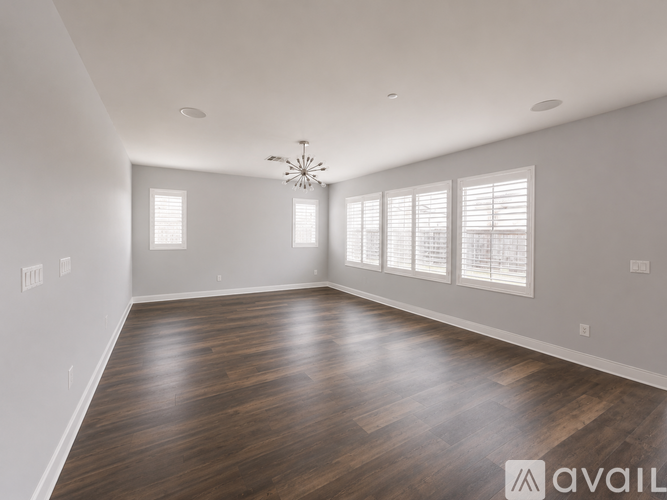A spacious room with wooden floors and a chandelier.