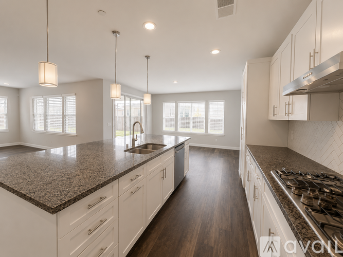 A modern kitchen with white cabinets and a dark granite countertop.