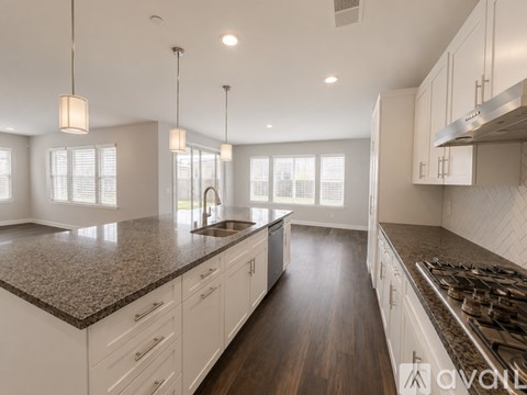 A modern kitchen with white cabinets and a dark granite countertop.
