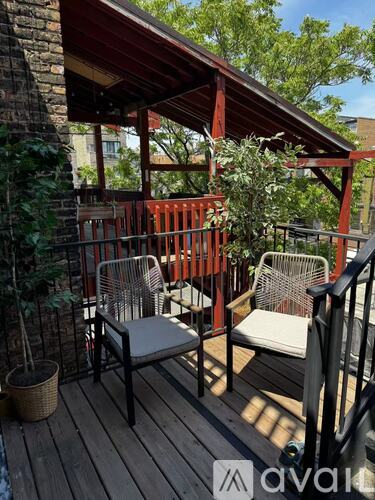 A wooden deck with a red railing and two chairs.