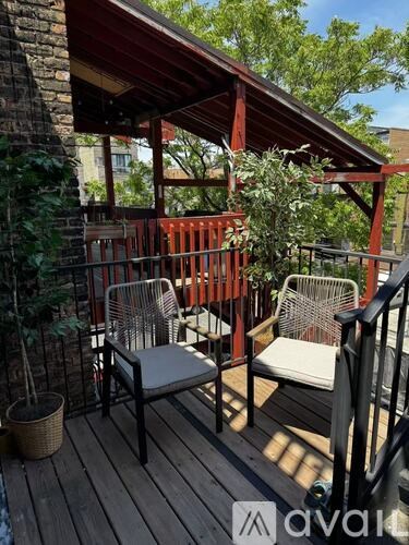 A wooden deck with a red railing and two chairs.