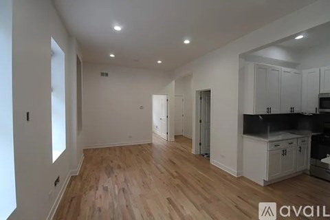 A spacious room with wooden flooring and white walls.