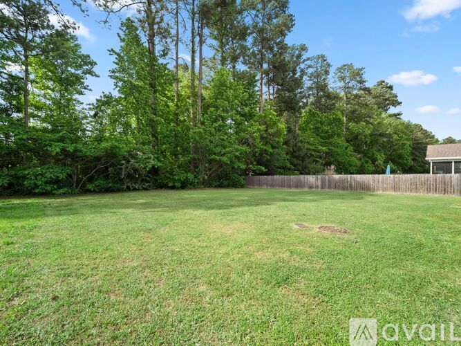 A grassy backyard with trees and a wooden fence.