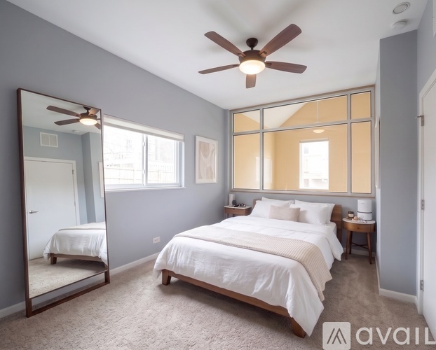 A bedroom with a large bed, a ceiling fan, and a mirror.