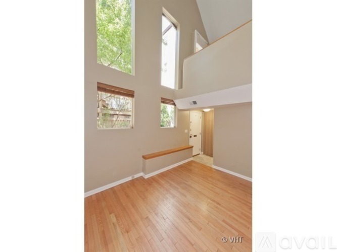 A room with wooden flooring and a window with a view of trees.
