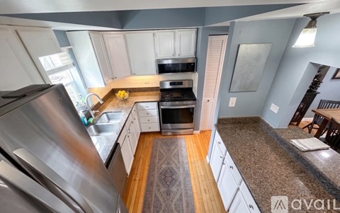 A kitchen with a stainless steel refrigerator and wooden flooring.