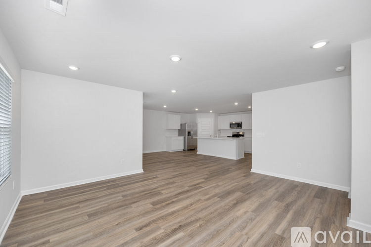 A spacious room with wooden flooring and white walls.