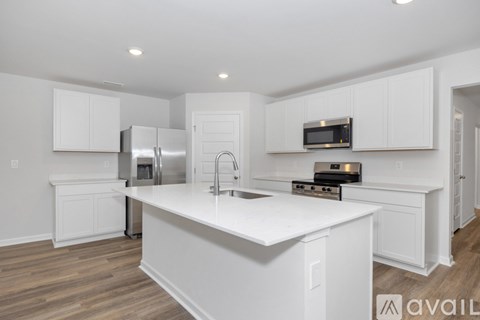 A kitchen with white cabinets and a white island with a sink.