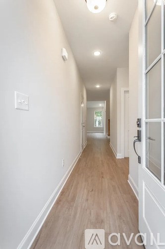 A long hallway with wood floors and white walls.