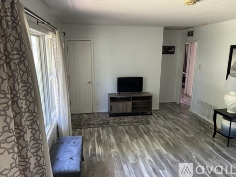 A living room with a television and a bench.