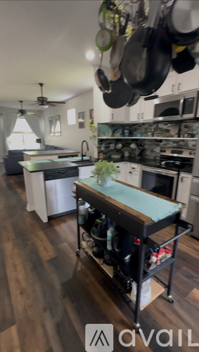 A kitchen with a table and a lot of pots hanging from the ceiling.