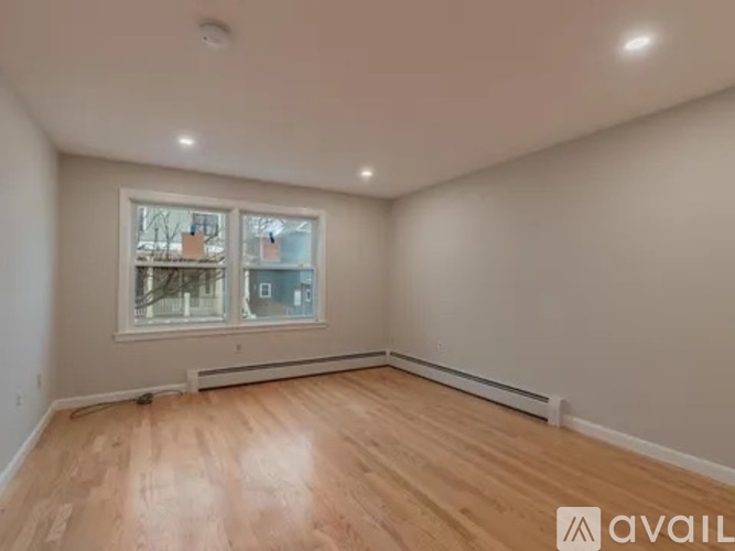 A room with wooden flooring and a window showing a view of a building outside.