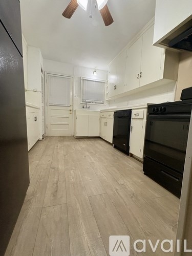 A kitchen with black appliances and white cabinets.