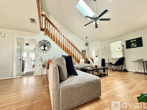 A living room with a grey couch and a fan on the ceiling.