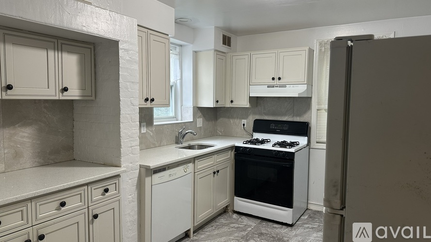 A kitchen with white cabinets and a black refrigerator.