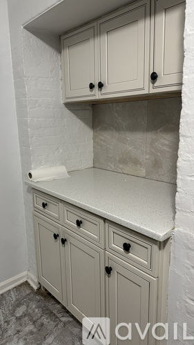 A kitchen with white cabinets and a marble countertop.