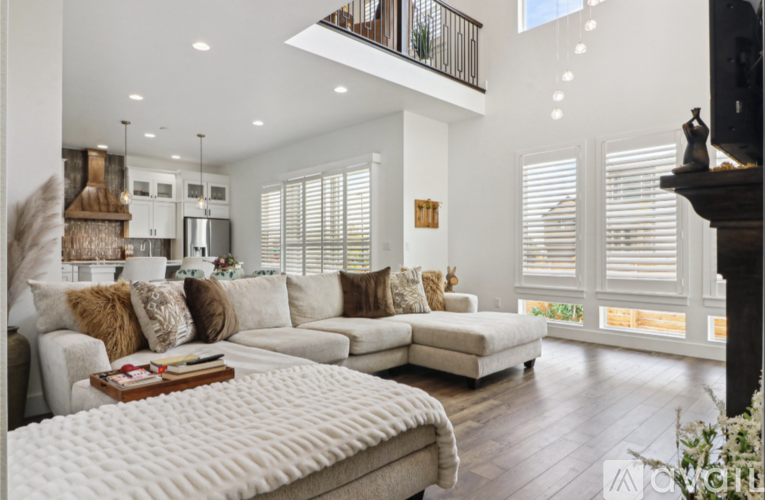 A well-lit, spacious living room with a large sectional sofa and a fireplace.