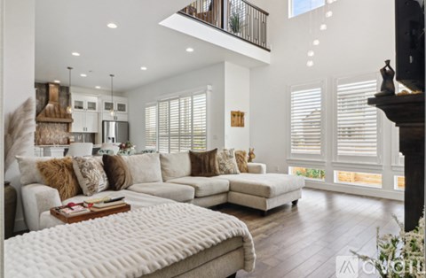 A well-lit, spacious living room with a large sectional sofa and a fireplace.