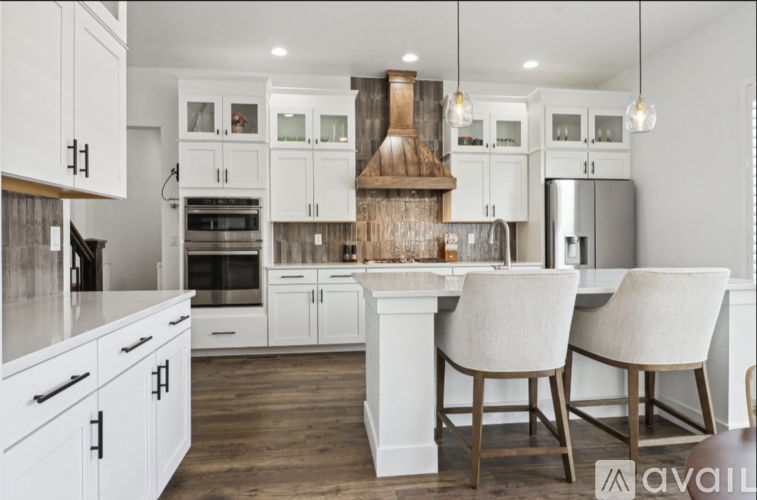 A modern kitchen with white cabinets and a wooden hood.