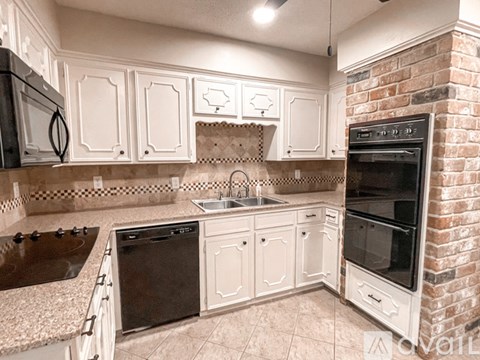A kitchen with white cabinets and a black dishwasher.
