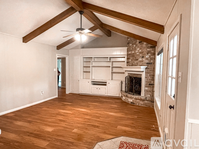 A living room with a fireplace and a ceiling fan.