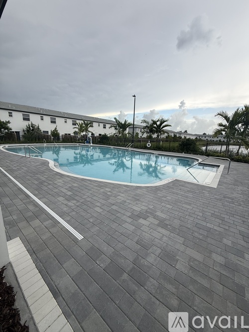 A swimming pool surrounded by a grey tiled deck.