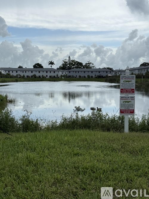 A sign in front of a body of water with a building in the background.