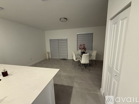 A white kitchen with a table and chairs in the middle of the room.