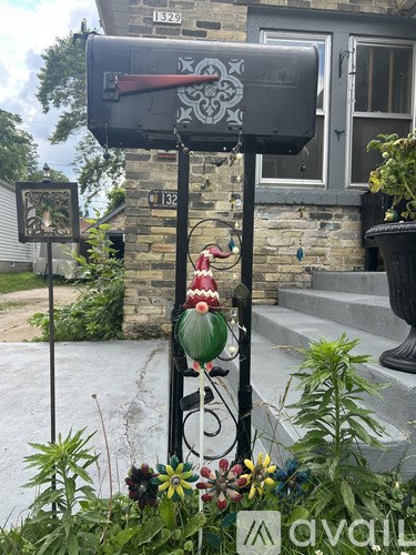A mailbox with a red design on it is on a black pole.