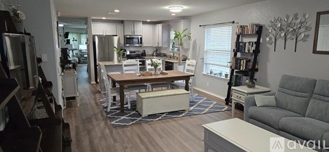 A living room with a grey couch and a dining table with chairs.