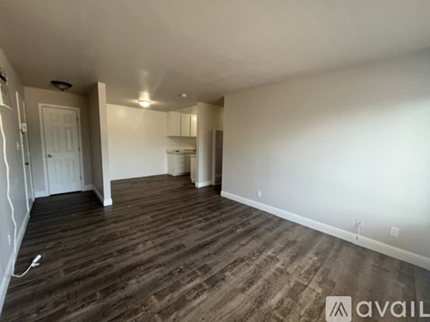 A spacious room with wooden flooring and white walls.