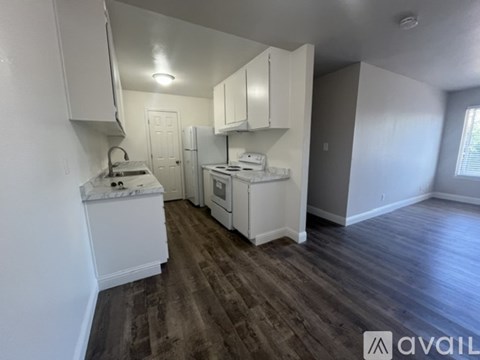 A kitchen with white cabinets and a wooden floor.
