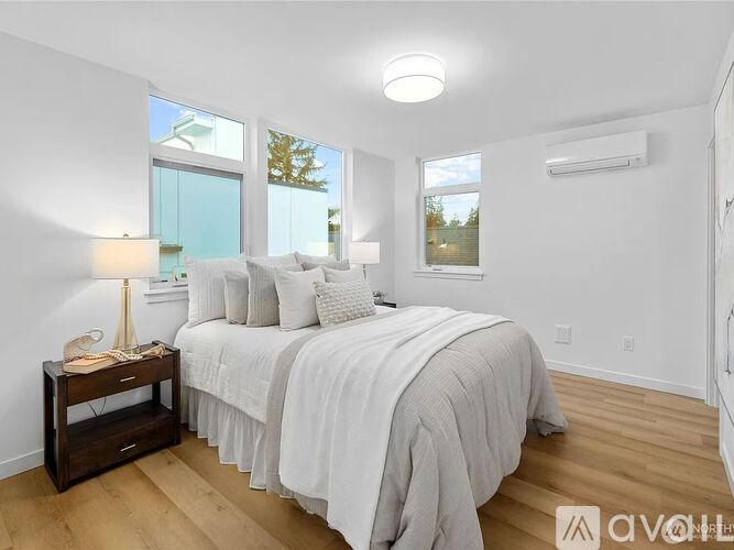 A bedroom with a large bed and a window overlooking a tree.