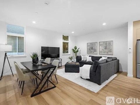A modern living room with a black table and chairs, a grey sofa, and a television.