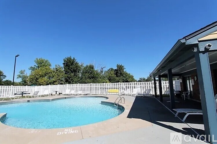 A pool with a white fence and a building in the background.