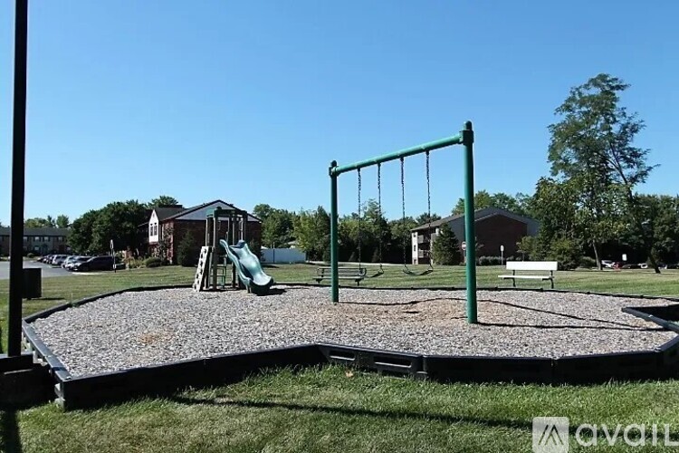 A playground with a green swing set and a green slide.