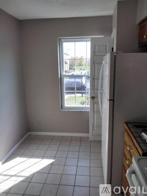 A kitchen with a white refrigerator and a window letting in light.
