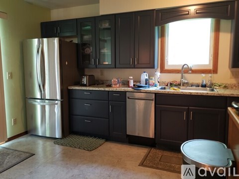 A kitchen with black cabinets and a stainless steel refrigerator.