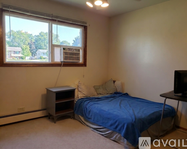 A bedroom with a bed, nightstand, and window with blinds.
