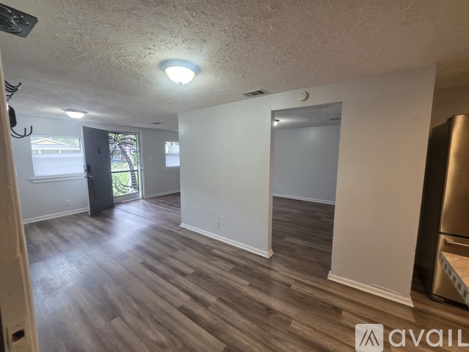A spacious room with wooden flooring and a sliding glass door leading outside.