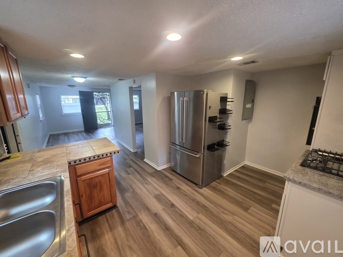 A kitchen with a stainless steel refrigerator and wooden cabinets.