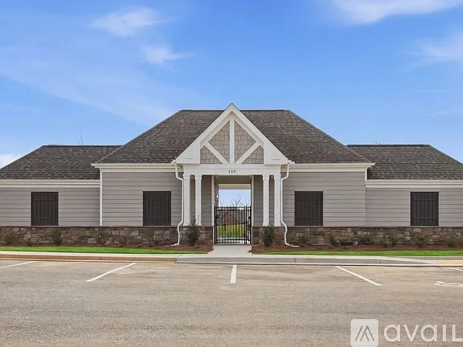 A building with a triangular pediment above the entrance and a parking lot in front.