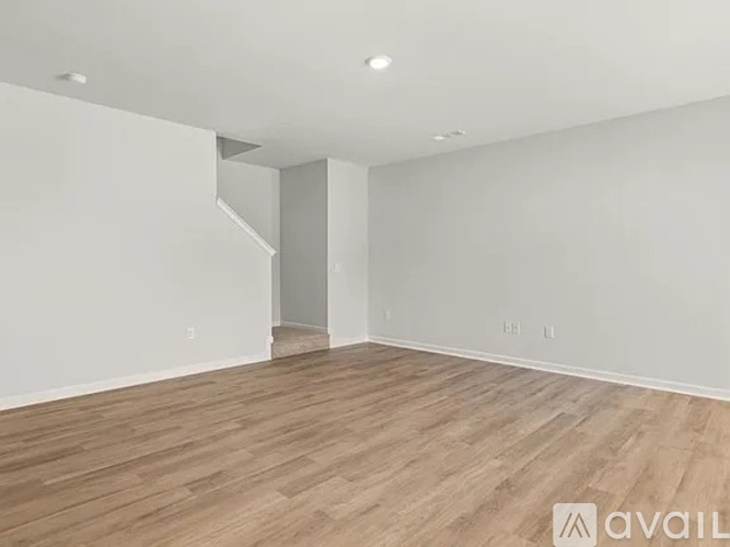 A spacious room with wooden flooring and white walls.