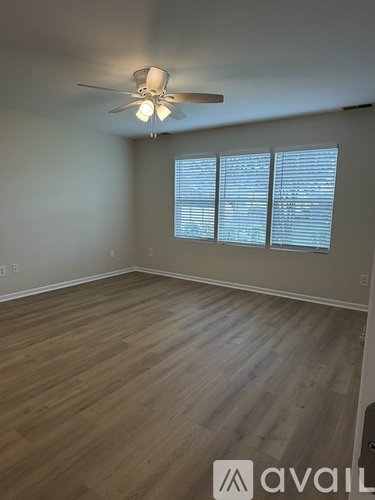 A room with a ceiling fan and wooden flooring.